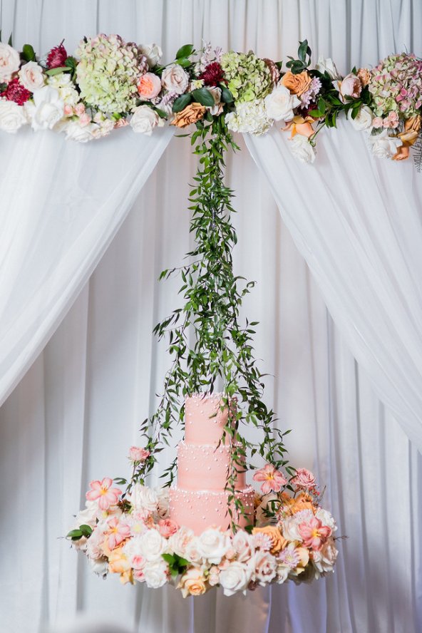 Cake hanging from floral display.