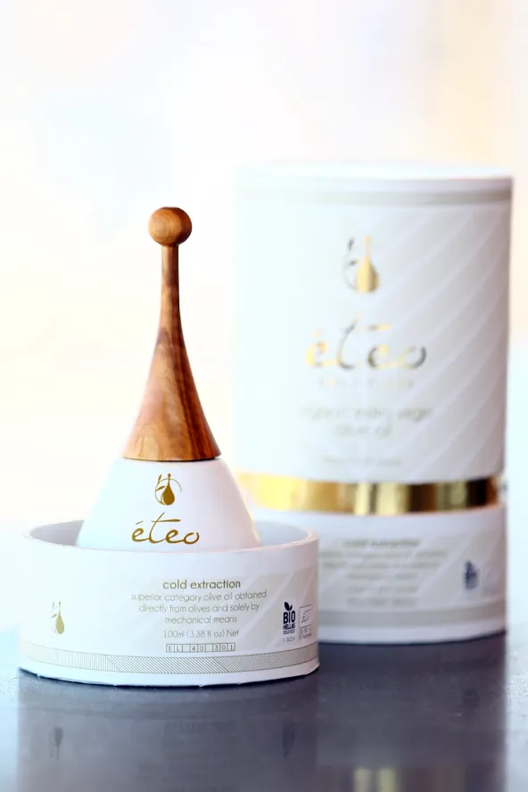 A decorative bottle of olive oil rests in its paper packaging