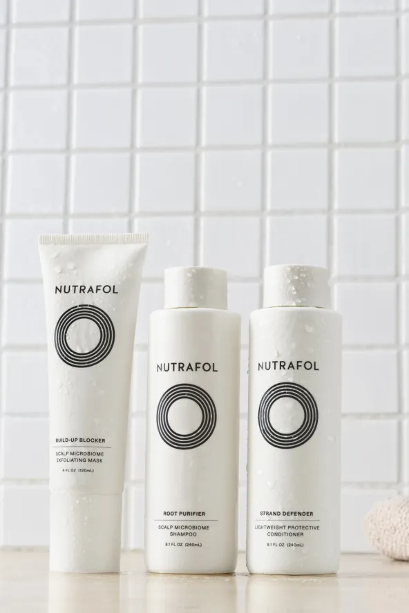 Three Nutrafol shampoo and scalp products displayed against white tile background.