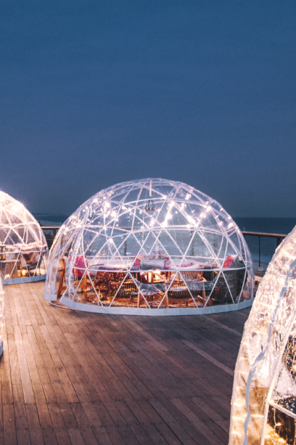 Warmly lit clear igloos against a dark blue evening sky at Gurney's Montauk Resort