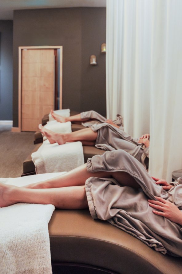 Three women in robes relaxing in Sanctuary Spa's Quiet Room before treatments.