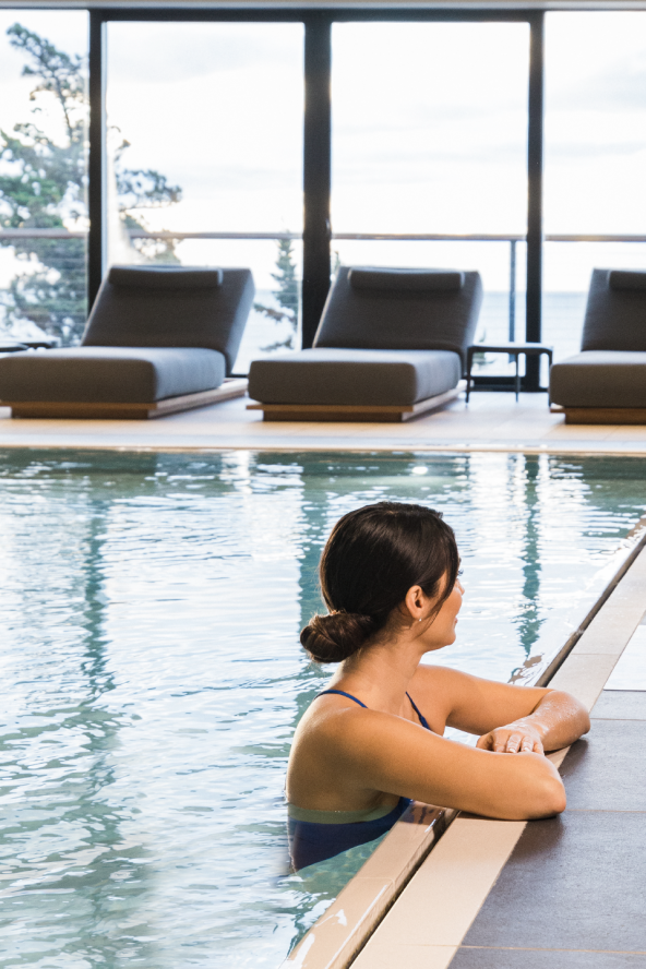 A woman rests on the edge of the indoor pool at The Seawater Spa