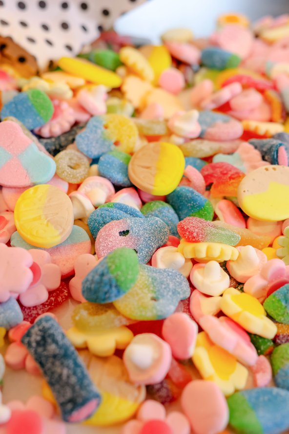 Assorted colorful candies scattered with a scoop and glass jar nearby.