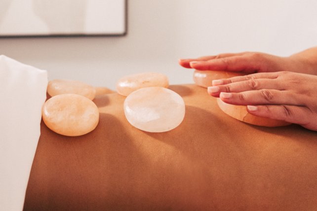 Woman receiving massage with white stones.