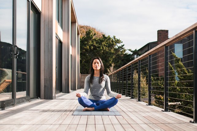 A woman in a seated yoga pose on the fitness deck at Gurney's Montauk Resort