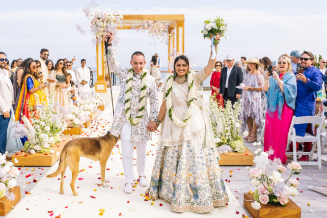 A couple walks down the aisle in traditional wedding attire.