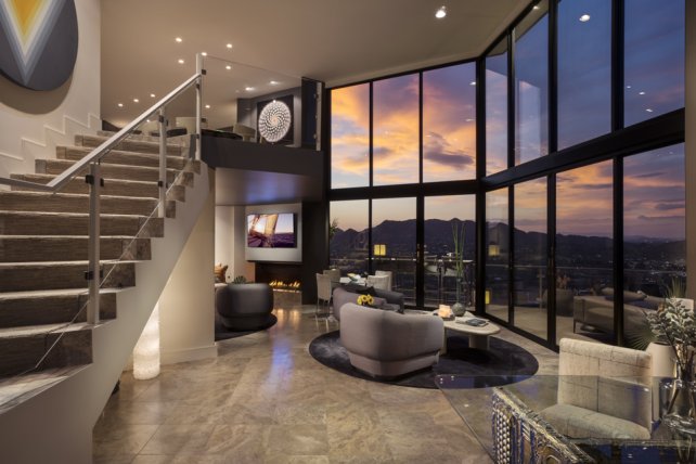 View from Villa Luna downstairs showing seating area with leather couch and chairs, television and floor-to-ceiling windows with spectacular valley sunset view.