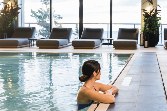 A woman leans against the edge of an indoor pool