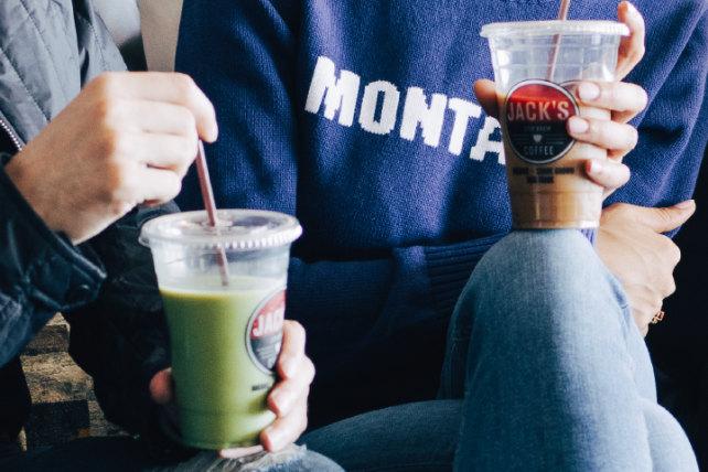 A close-up of two people drinking iced drinks