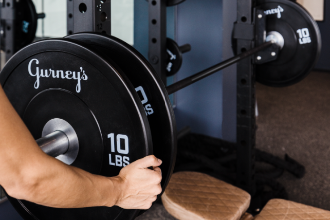 A close-up of a person racking weights at the Gurney's Montauk fitness center