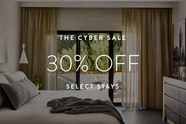 Modern bedroom with large window, beige curtains, and neatly made bed. Text reads "The Cyber Sale 30% Off Select Stays."