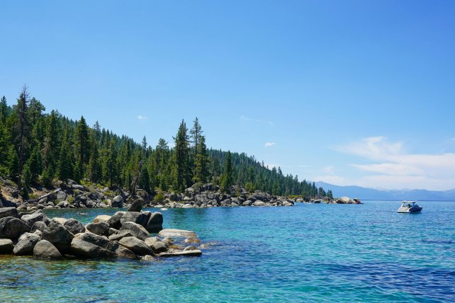 Image of Lake and side of land with rocks and trees. 