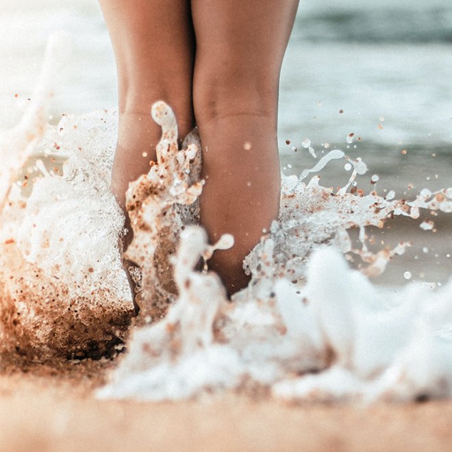 Splashing waves around someone's legs at the beach.