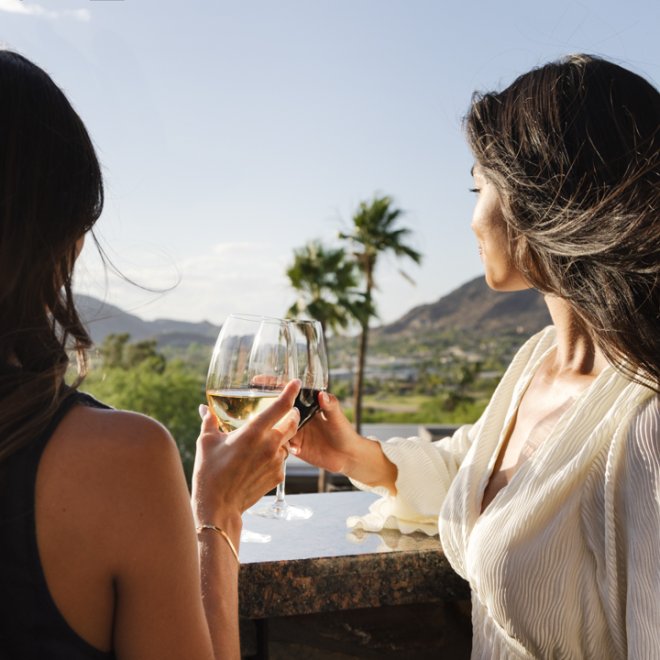 Two women enjoying the afternoon view from elements balcony with glasses of wine.