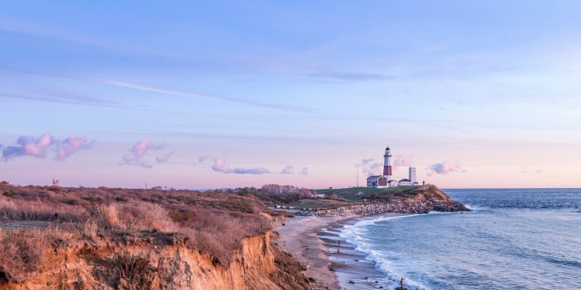 Waves crashing on fall shoreline with lighthouse in the background.