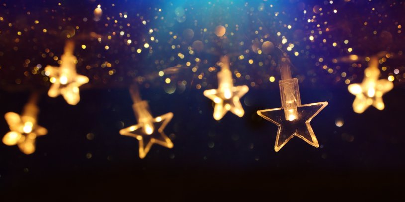 Glowing gold stars with lights inside hanging in front of blue background.