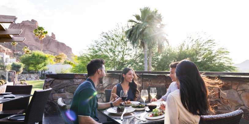 Two couples dining outdoors on elements sunset patio during sunset.