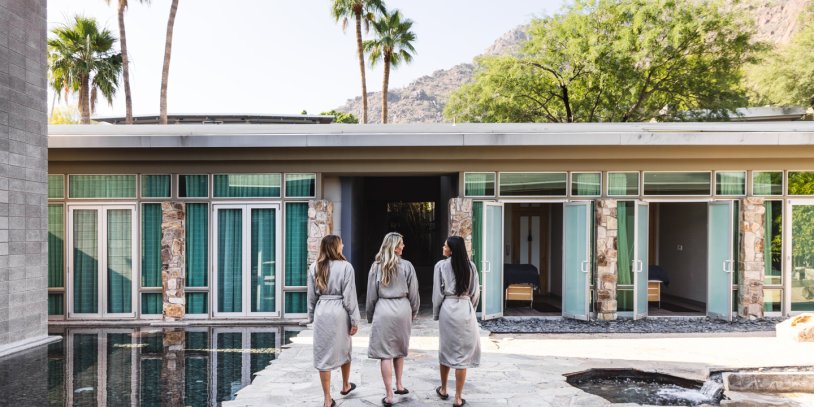 Three woman in spa robes walking through Sanctuary Spa's Zen Garden courtyard before treatments.