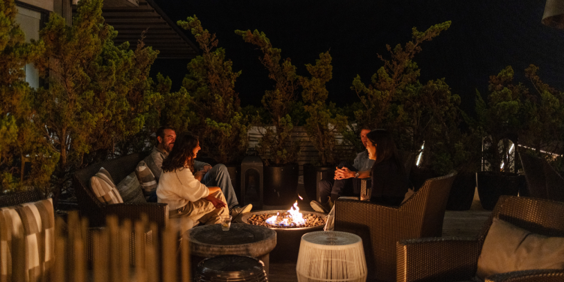 A group of people gather round the fire nighttime at Gurney's Montauk Resort