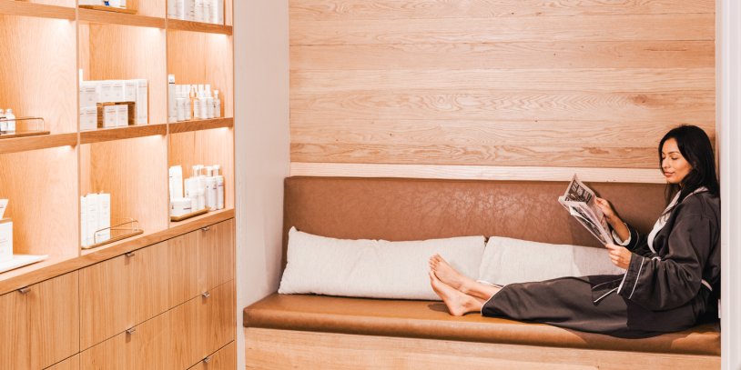 Woman lounging in robe and reading a magazine at Seawater Spa.