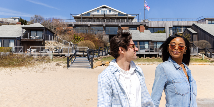 A couple walks on the sand on a sunny day at Gurney's Montauk Resort