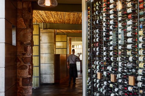 Sanctuary's wine wall with a server walking past.