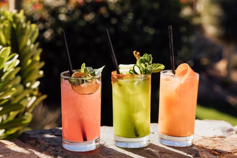 Three jade bar summer cocktails displayed outside.