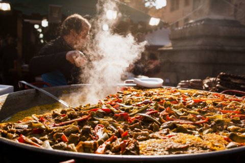 Man cooking Paella on outdoor grill.