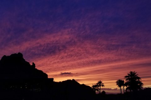 Silhouette of Praying Monk against pink and purple Arizona sunset.