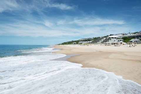Waves crashing along shoreline with Gurney's Montauk Resort and Seawater Spa in background.