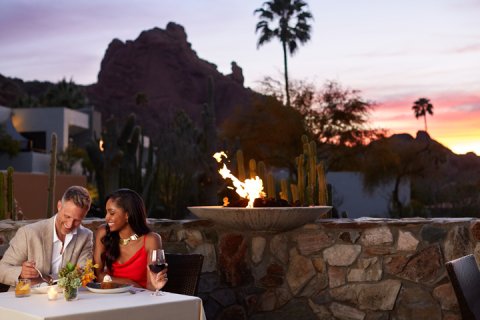 Couple enjoying a romantic meal at elements with sun setting over Praying Monk in background.