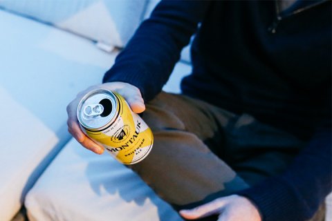 Man holding can of beer while seated at Gurney's Montauk Resort
