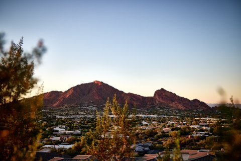 Long distance view of Camelback Mountain and surrounding valley glowing red in the setting sun.