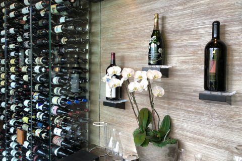 Sanctuary wine wall with three magnum bottles displayed, flowers and glass wine wall.