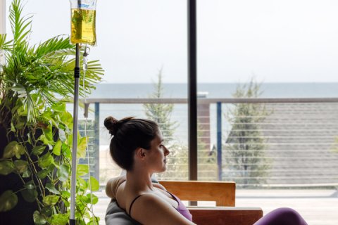 Woman in lounge wear relaxing at seawater spa poolside with IV Drip.