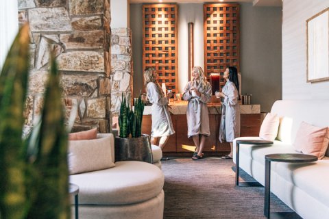 Three woman in spa robes enjoying tea in women's locker room before spa treatments.