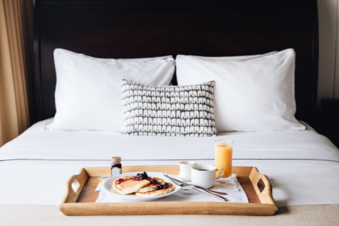 A tray of blueberry pancakes sits atop a crisp white bed