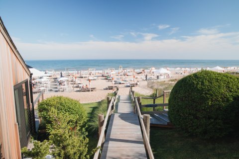 View down wooden walkway to the beach lined with chairs and umbrellas at Gurney's Montauk