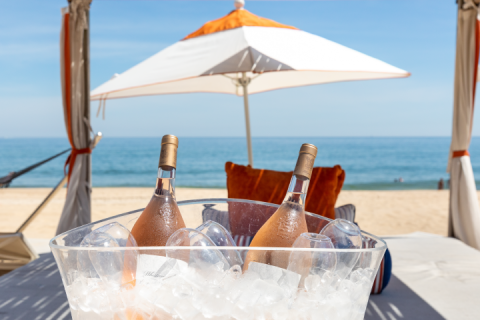Two bottles of wine set against an umbrella and an ocean backdrop
