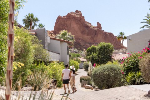 Couple in comfortable attire walking through lush, desert landscape outside Mountain Casitas and Suites.
