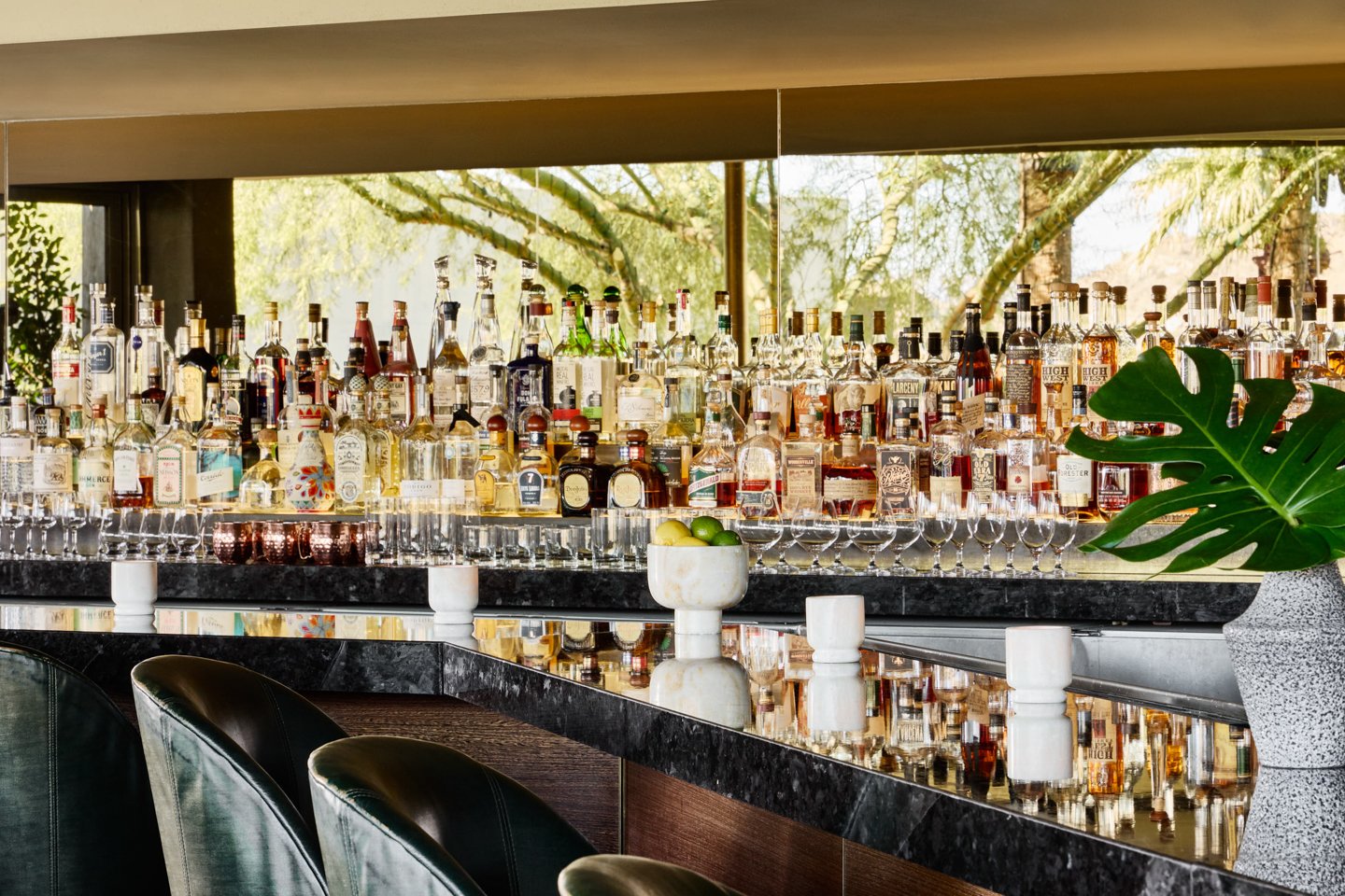 Glasses and spirits lined up behind jade bar.