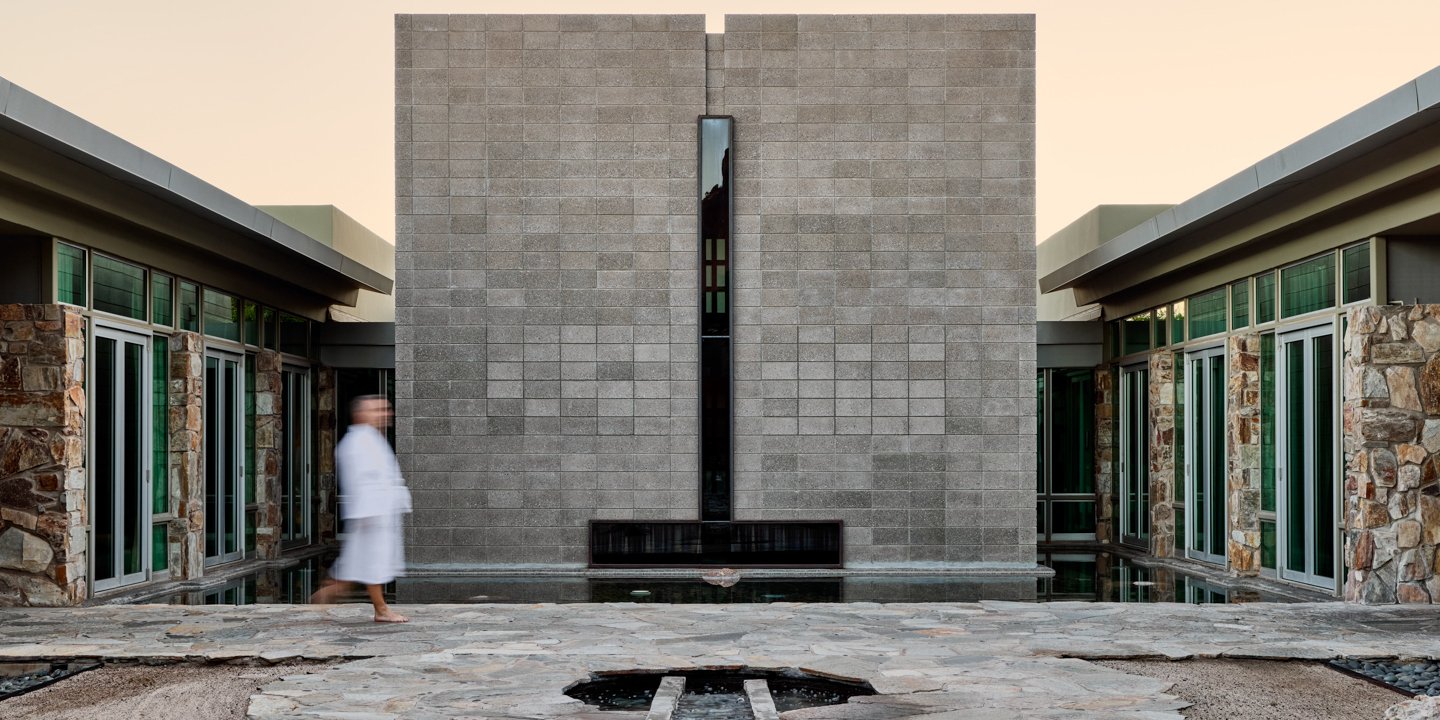 Man in robe walking through Sanctuary Spa Zen Courtyard.