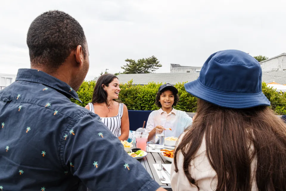 A group of people sitting at a table outdoors, eating and conversing.