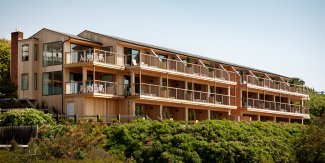 Wide exterior of building showing private balconies looking out towards the beach