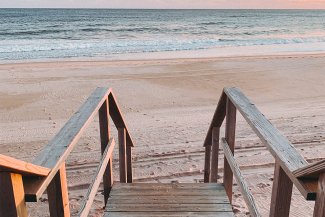 Wooden stairs leading down to the beach and ocean, taken at sunset