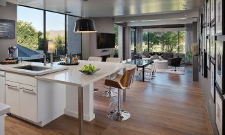 Full kitchen with island and stools and connecting dining and living room.