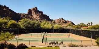 Couple playing tennis with Praying Monk in the background.