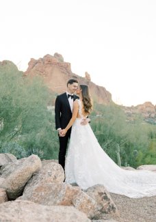 Bride and groom embracing with Praying Monk in the backdrop.