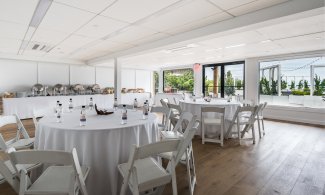 Latitude meeting space with wood floors, circular tables with white linen and water bottles and buffet setup.