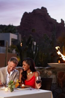 Couple enjoying a romantic meal at elements with sun setting over the mountain in background.